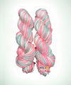 Two twisted skeins of variegated yarn with pink, white, and light blue-green stripes, displayed against a solid white background. A logo for 'NTCS Natural Textiles' is visible on the bottom right of the skeins.